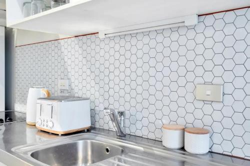a kitchen counter with a sink and a mixer at Metro Living Apt near Skytower and Parking in Auckland