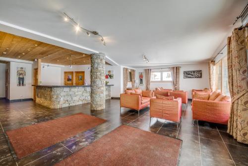 a living room with orange chairs and a stone fireplace at Résidence Almes1 et Almes 2 in Tignes