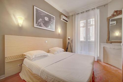 une chambre avec un grand lit blanc et une fenêtre dans l'établissement Appartement Cannes Centre, à Cannes