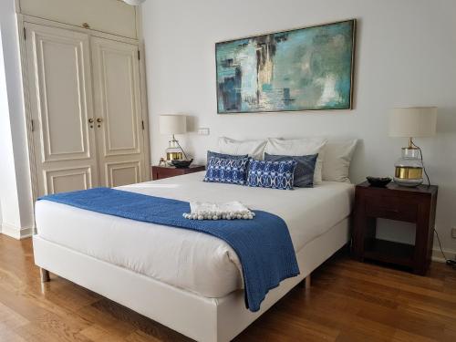 a bedroom with a large white bed with blue pillows at Modern Apartment Gulbenkian in Lisbon