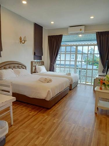 a hotel room with two beds and a balcony at Promporn Boutique Hotel in Nan