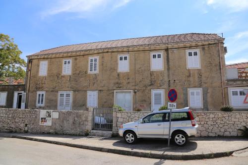 a white car parked in front of a brick building at Coosy rooms KATARINA in Lumbarda