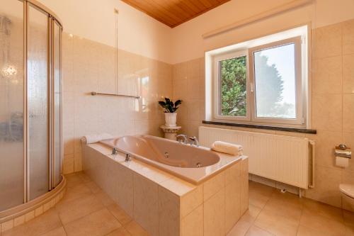 a bathroom with a large tub and a window at Refúgio Rural - Eco Villa in Caldas da Rainha
