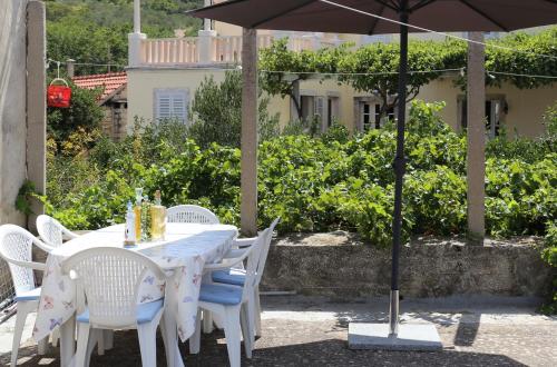 a white table with white chairs and an umbrella at Coosy rooms KATARINA in Lumbarda