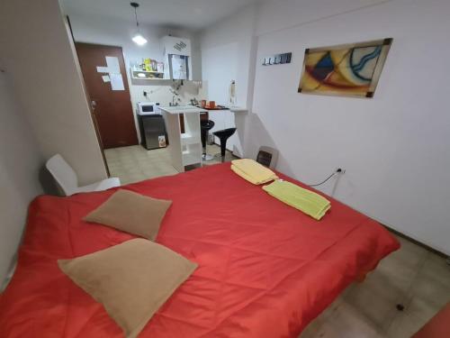ein rotes Bett mit zwei gelben Kissen darüber in der Unterkunft Departamento,Centro de Cordoba, monoambiente,a 100mts del Patio Olmos in Cordoba