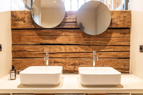 two sinks in a bathroom with two mirrors at Wassermann in Sesto