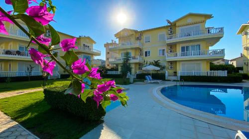 a villa with a swimming pool and pink flowers at Belek King Cleodora Apartment in Belek