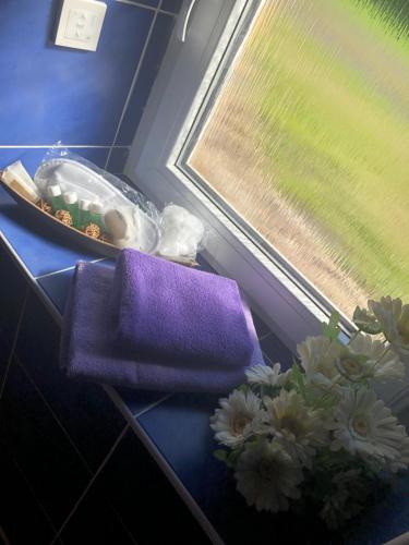 a table with a purple towel and flowers next to a window at Ubytování v soukromí rodinné vily v Děčíně in Děčín