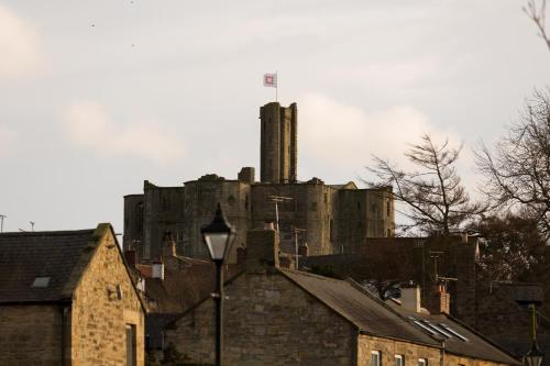 an old castle sitting on top of a city at Warkworth House Hotel in Warkworth