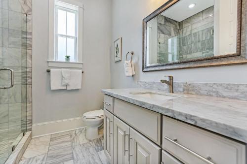 a bathroom with a sink and a toilet and a mirror at Hosteeva Amazing 4 BR Modern Condo with Balcony Near Frnch Quarter in New Orleans