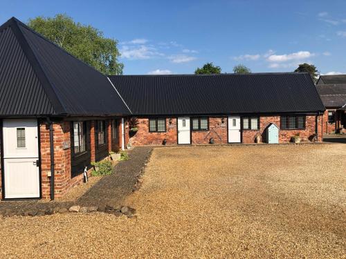 a brick barn with white doors and a black roof at Hunt House Quarters in Kilsby