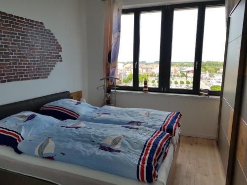 a bedroom with a bed with blue sheets and windows at Sunshine Speicherresidenz Barth in Barth