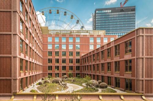 a building with a garden in front of a ferris wheel at gambino hotel WERKSVIERTEL in Munich