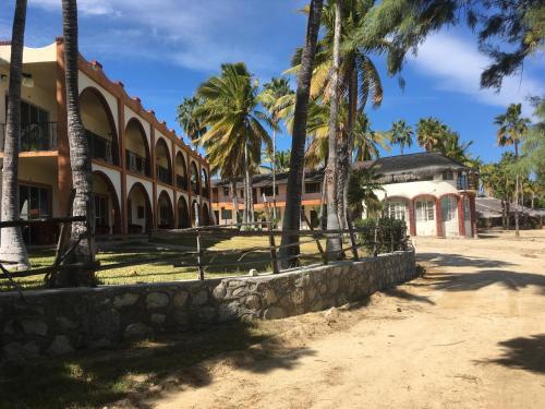 a building with palm trees and a stone wall at Hotel Rancho Buenavista in Los Barriles
