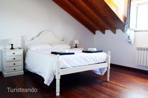 a bedroom with a white bed with two towels on it at Chalet Adosado Proa - Parking y jardín con impresionantes vistas a la Ría de San Vicente de la Barquera in San Vicente de la Barquera
