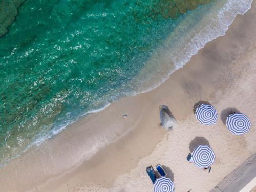 an overhead view of a beach with umbrellas and the ocean at Hotel Ipomea Club in Capo Vaticano