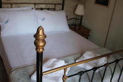 a bed with white sheets and a black and gold pole at Lazaros Stonehouse in Pano Lefkara