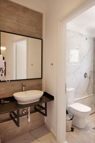 a bathroom with a sink and a toilet and a mirror at Lumi Hotel in Sarandë