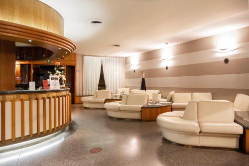 a waiting room with white chairs and a salon at Albergo Milano in Boario Terme