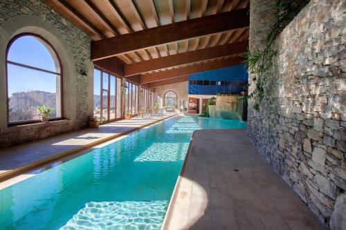 uma piscina de beiral infinito numa casa com uma parede de pedra em L'Avenc Benestar Rural em Tavertet