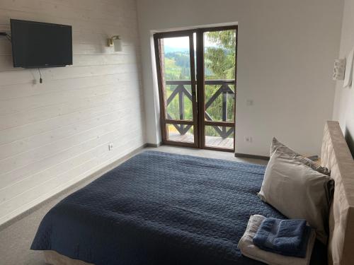 a bedroom with a bed and a large window at Panorama Karpat in Yablunytsya