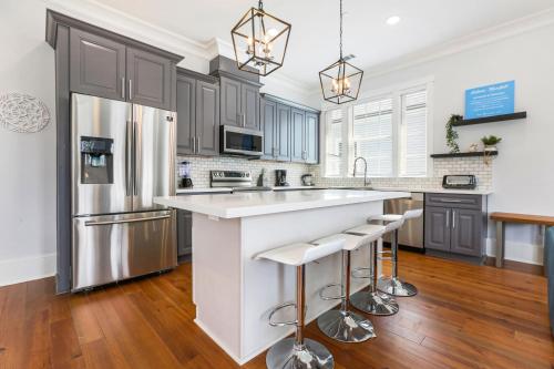 ニューオーリンズにあるHosteeva Brand New Condo with a Pool Steps to St Charles Aveの白い大きな島(バースツール付)のあるキッチン