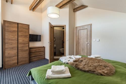 Chalets Royal, Tatranská Lomnica في تاترانسكا لومنيكا: غرفة نوم بسرير اخضر عليها مناشف