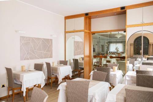 a restaurant with white tables and chairs and a mirror at Albergo Milano in Boario Terme