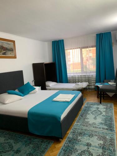 Habitación de hotel con 2 camas y cortinas azules en Pensiunea Ruxi, en Curtea de Argeş