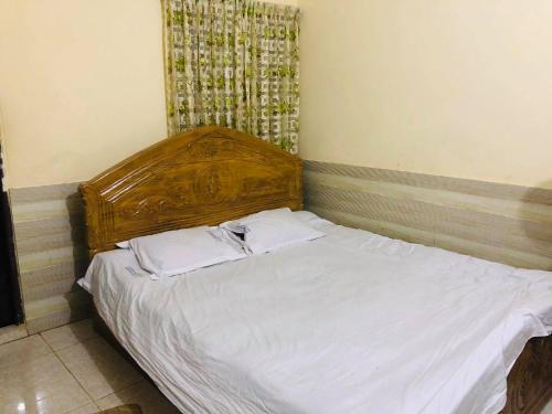 a bed with a wooden headboard in a bedroom at Hotel Regal Palace in Chittagong
