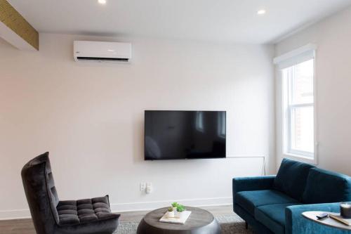 a living room with a couch and a tv on a wall at Live Like a Local in this Superb Loft by Den Stays in Montréal