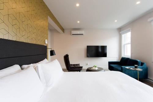 a bedroom with a bed and a couch and a tv at Live Like a Local in this Superb Loft by Den Stays in Montréal