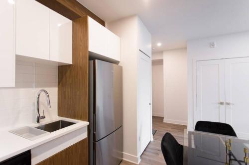 a kitchen with a stainless steel refrigerator and a sink at Live Like a Local in this Superb Loft by Den Stays in Montréal