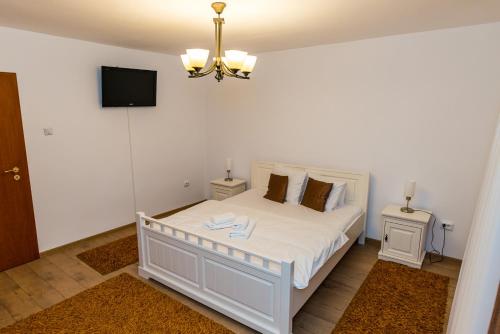 a bedroom with a white bed with a tv on the wall at CASA LUCA in Moldova Nouă