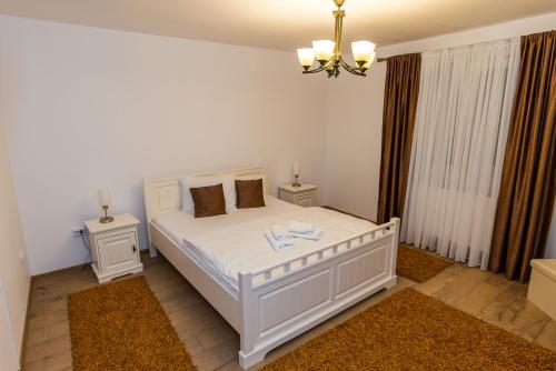 a white bedroom with a white bed and two tables at CASA LUCA in Moldova Nouă