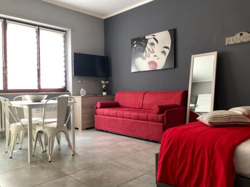 a living room with a red couch and a table at HappyHome Appartamento 4 posti letto Rivarolo Canavese in Rivarolo Canavese