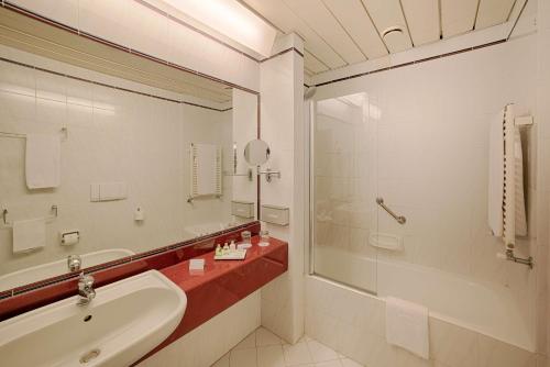 a bathroom with a sink and a tub and a mirror at NH Ancona in Ancona