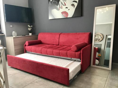 a red couch sitting in a living room at HappyHome Appartamento 4 posti letto Rivarolo Canavese in Rivarolo Canavese