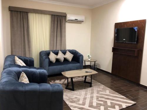 a living room with two blue couches and a tv at هبي نيس للوحدات السكنية in Medina