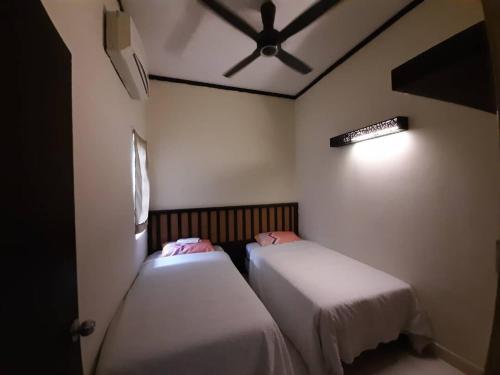 een kamer met 2 bedden en een plafondventilator bij Gold Coast Morib Resort Apartment Ezzy in Kampong Tanjong Pechah