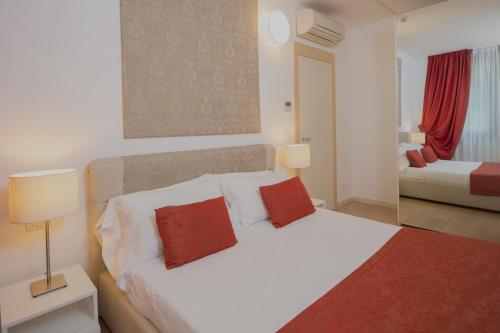 - une chambre avec un lit blanc et 2 oreillers rouges dans l'établissement Di Sabatino Resort - Suite Apartments & Spa, à Ascoli Piceno