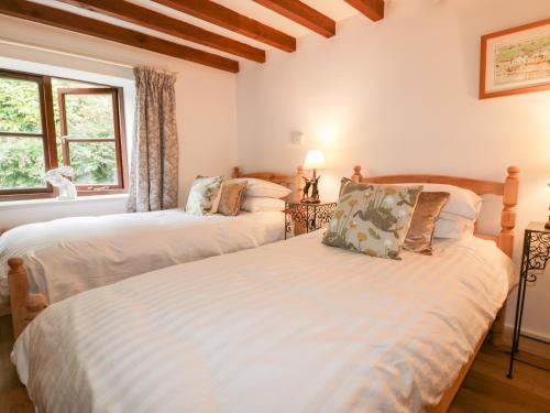 two twin beds in a room with a window at Ribby Barn in Lostwithiel