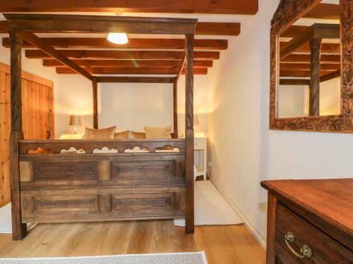 a bedroom with a wooden bed with a mirror at Ribby Barn in Lostwithiel
