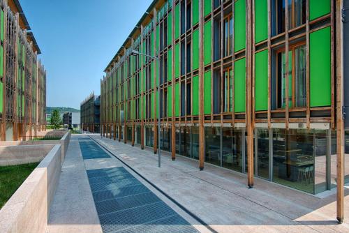 a large green building with glass windows on a street at NH Trento in Trento