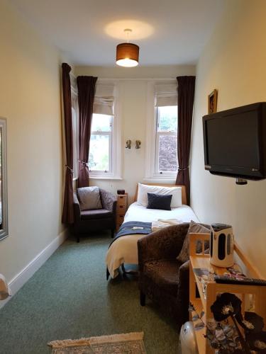 a bedroom with a bed and a tv and a couch at The Palms Guest house in Torquay