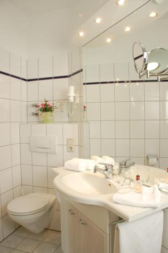 a bathroom with a sink and a toilet and a mirror at Landhotel Behre in Lehrte