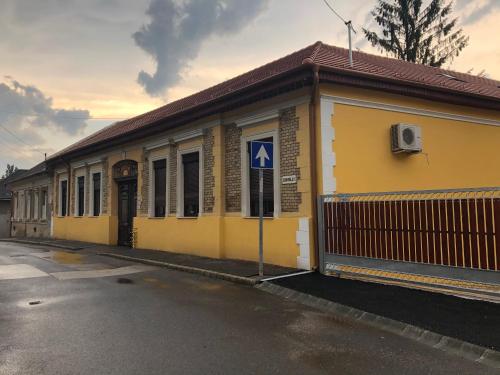 a yellow building with a blue sign on it at Rigó Lak in Miskolc