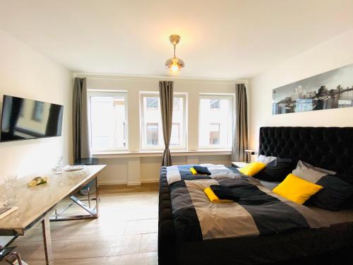 a bedroom with a bed and a table and windows at Apartments City Center Düsseldorf in Düsseldorf