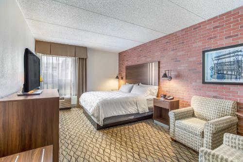 a hotel room with a bed and a tv at Burrstone Inn, an Ascend Collection Hotel in Utica