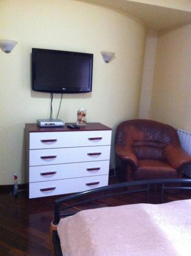 a bedroom with a dresser with a television and a chair at Sunny House in Skopje